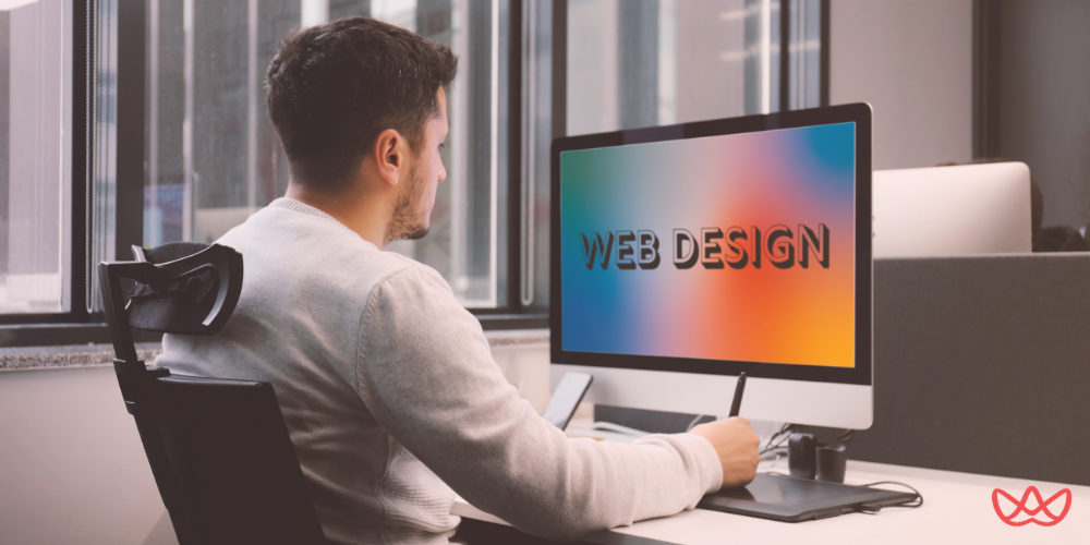 Web designer working at a computer displaying colorful "WEB DESIGN" text on the screen