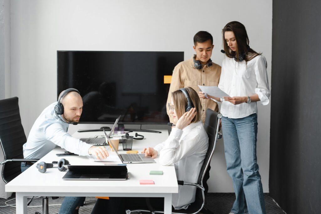 Team of professionals collaborating in a modern office, using headsets and laptops to discuss customer-focused strategies—ideal visual for a Customer Relationship Manager (CRM) Resume Template.