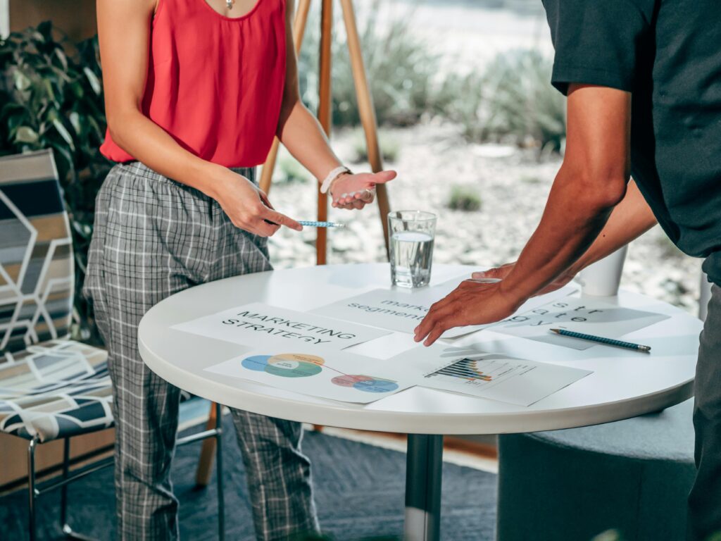 Two professionals collaborating on a marketing strategy with charts and reports on a table, representing a Digital Marketing Consultant Resume Template in action.
