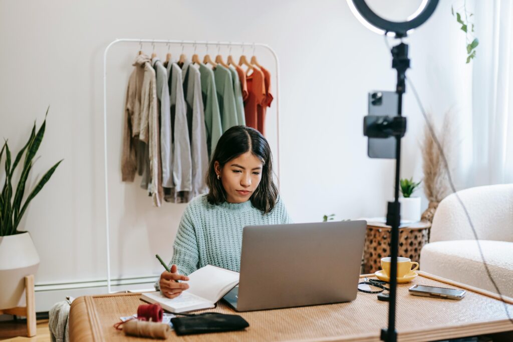 A person works on a laptop with a notebook and pen, suggesting the creation or use of a Blog Manager Resume Template.