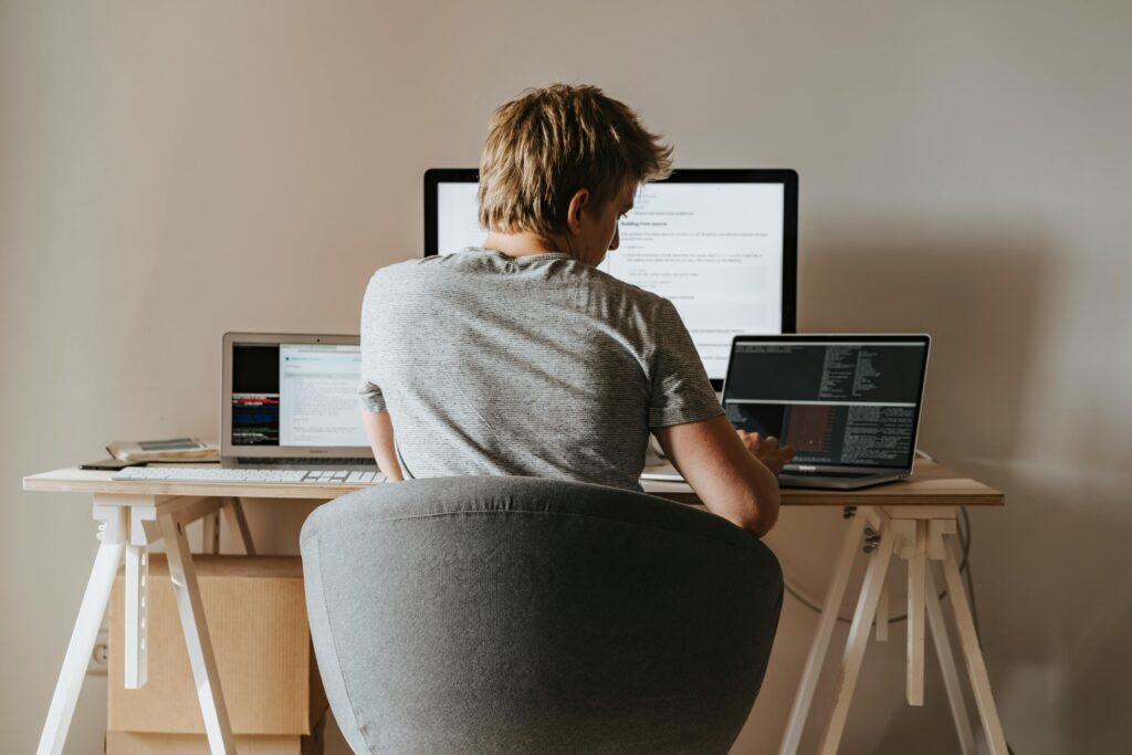 Man sitting at a desk with multiple screens, researching Offshoring Explained: Full Guide on his computer.