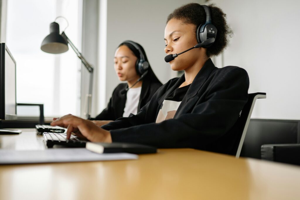 Customer service representatives working at computers in a professional setting, representing support teams involved in managing outsourced payroll costs.