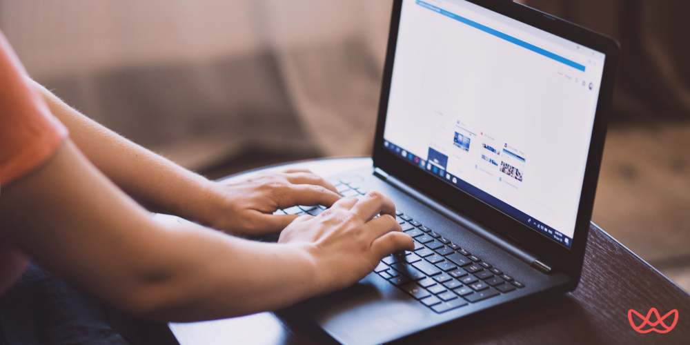 Close-up of a person's hands typing on a laptop keyboard, with the laptop screen showing what appears to be a web browser or application, and the text "Hired by Offshore Accountant Comprehensive Guide" is visible on the image.