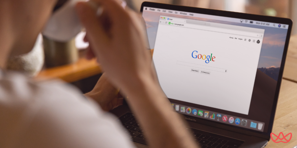 A person looking at a laptop screen displaying the Google search homepage. The overall image suggests online research or digital marketing activity, with the text "Multilingual SEO Services Expand Your Global Reach" partially visible in the bottom right corner.