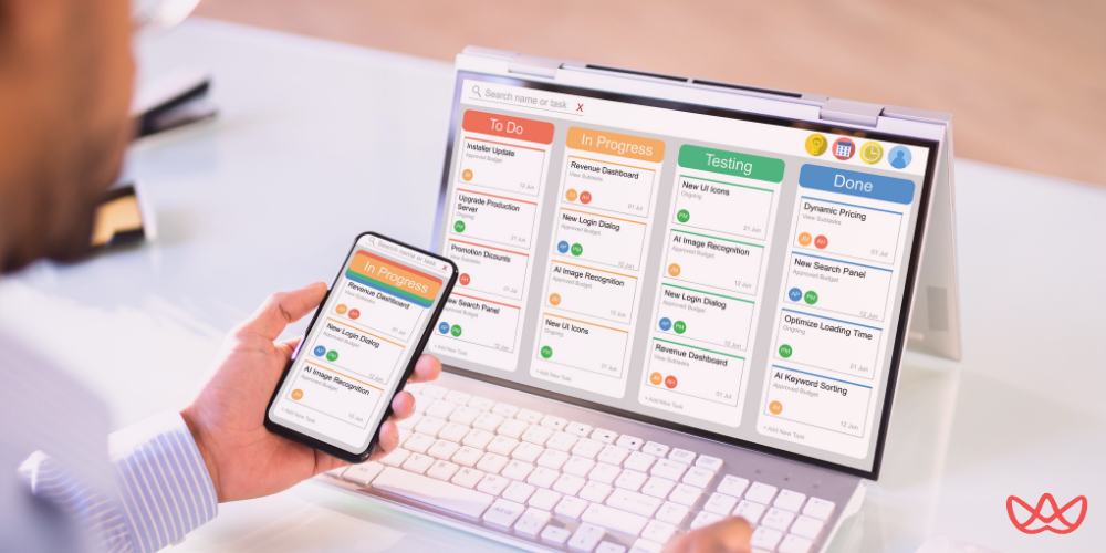 A person from behind, looking at a laptop screen displaying a project management dashboard with "To Do," "In Progress," "Testing," and "Done" columns, along with various tasks. They are also holding a smartphone displaying a similar interface. The image also contains the text "Project Management Agency Your Guide to Hiring the Right Partner in 2025."