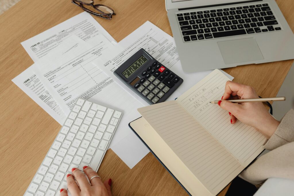 A close-up of a desk with various financial documents, including forms and receipts, along with a black calculator and a pair of eyeglasses, suggesting financial planning or accounting tasks.