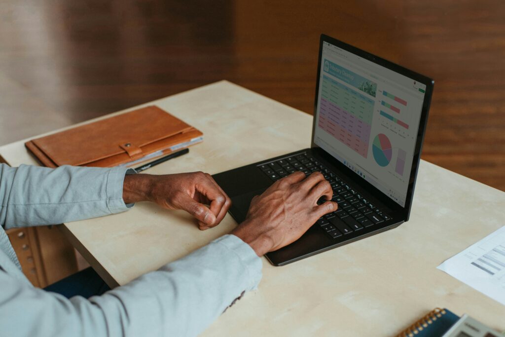 A tidy desk setup featuring a laptop with a digital clock displaying "3 09", a stack of books, eyeglasses, and a smartphone, suggesting a focused and organized workspace.